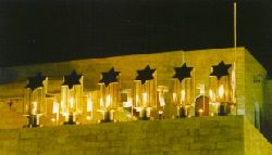 Sjoa-monument bij de Westmuur in Jeruzalem. Tussen de 6 eeuwige vlammen staan de letters van het Hebreeuwse woord Jitzkor (gedenk)!